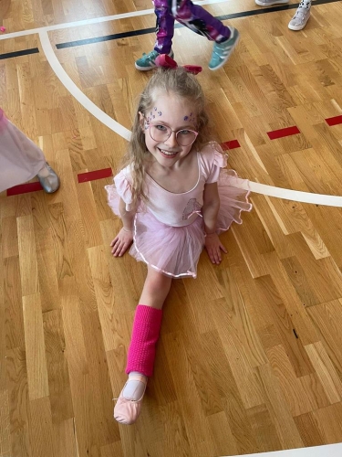 Dziewczynka przebrana za baletnicę robi szpagat 