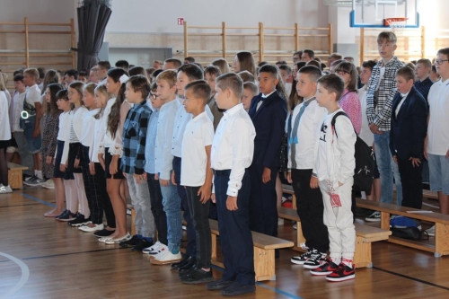 Grupa uczniów stoi na baczność podczas hymnu narodowego. 