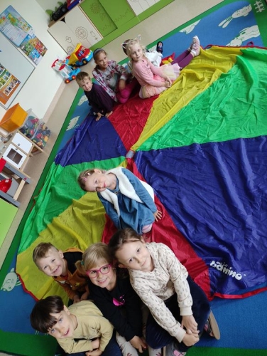 Grupa przedszkolaków podczas zabawy z chustą. 